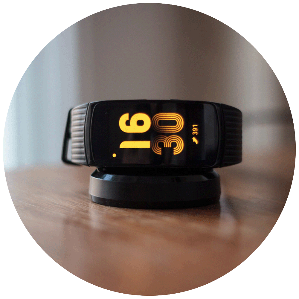 Samsung Gear Fit 2 Pro on charging dock on wooden table
