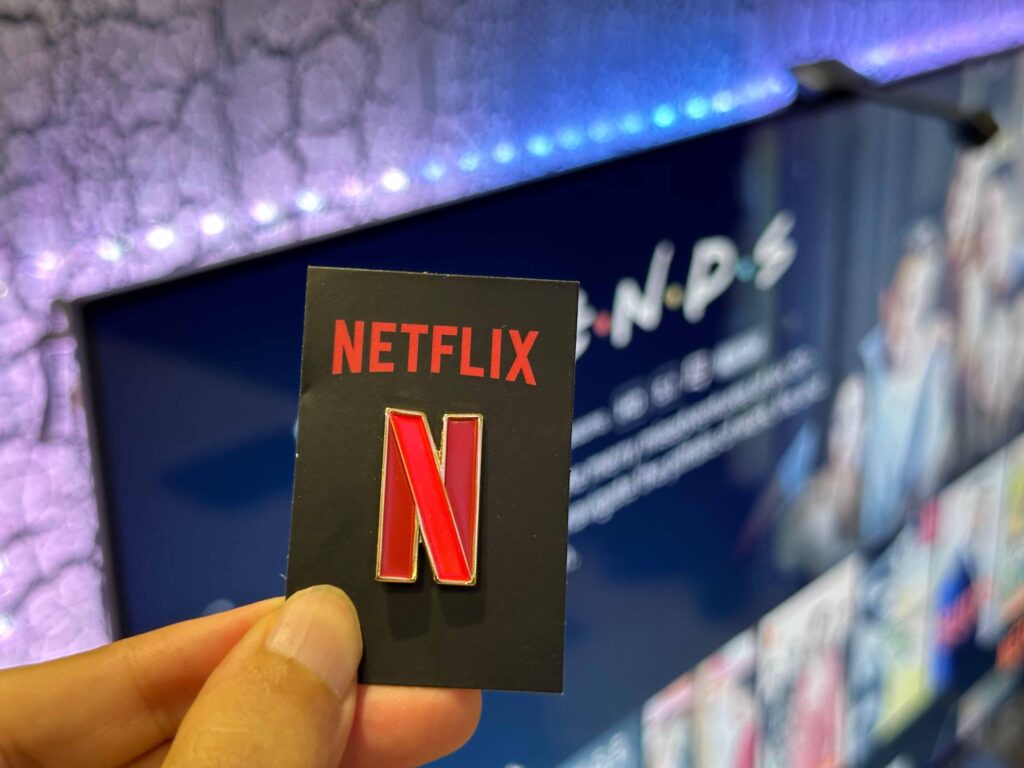 Netflix enamel pin in front of TV with Friends show